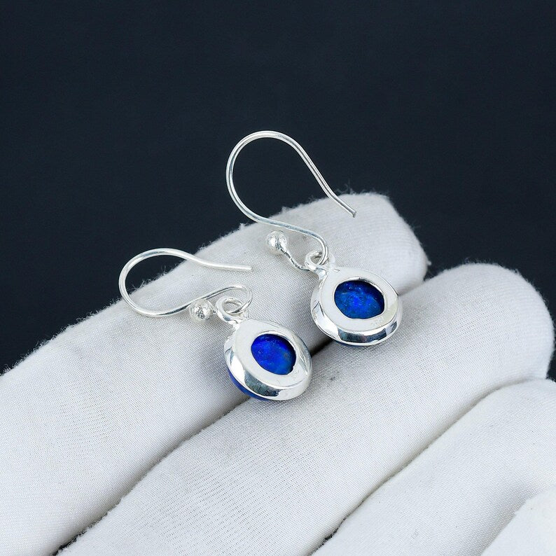 Silver earrings with blue gemstones on a white surface