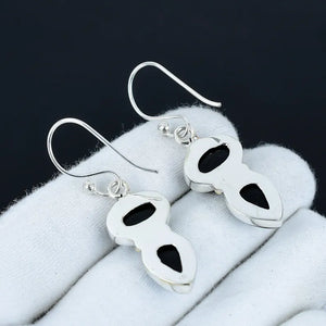 Pair of silver earrings with black stones on a white surface
