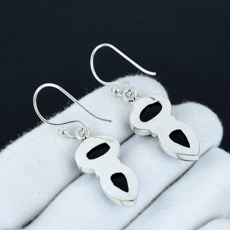 Pair of silver earrings with black stones on a white surface