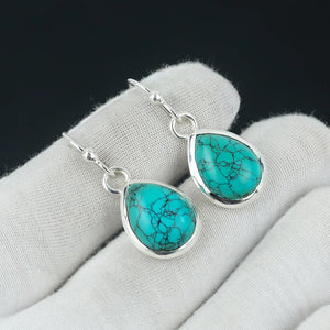 Turquoise earrings with silver hooks on a gray surface