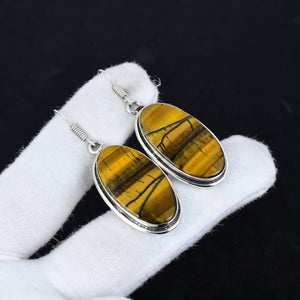 Tiger's eye earrings with silver settings on a white cloth against a black background