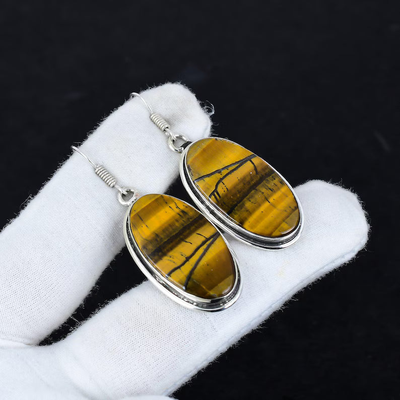 Tiger's eye earrings with silver settings on a white cloth against a black background
