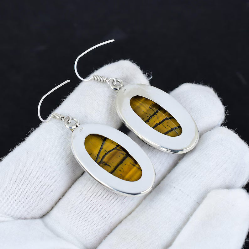 Silver earrings with yellow stone inlays on a white surface