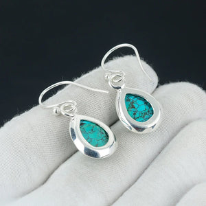 Silver earrings with turquoise stones on a gray surface