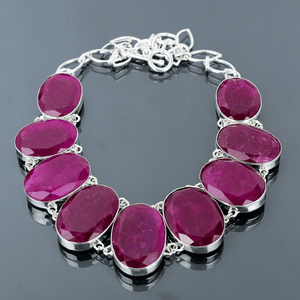 Silver bracelet with pink gemstones on a reflective surface