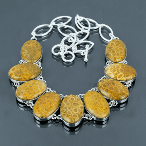 Necklace with yellow stone pendants on a reflective surface