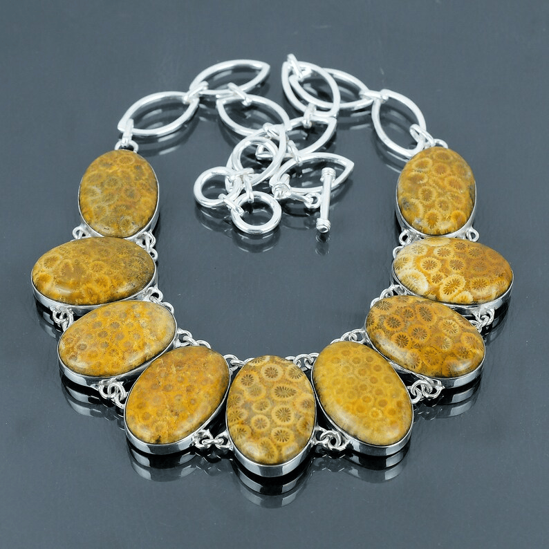 Necklace with yellow stone pendants on a reflective surface