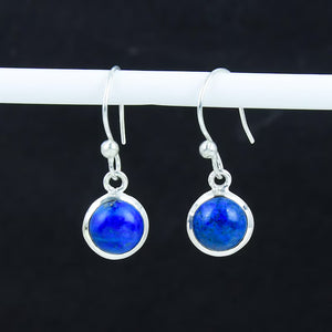 Pair of silver earrings with blue gemstones on a dark background