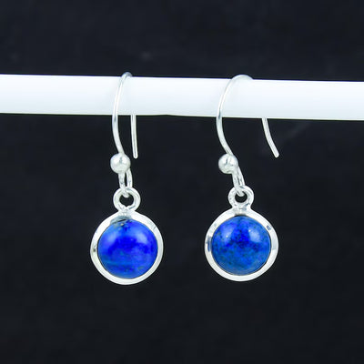 Pair of silver earrings with blue gemstones on a dark background