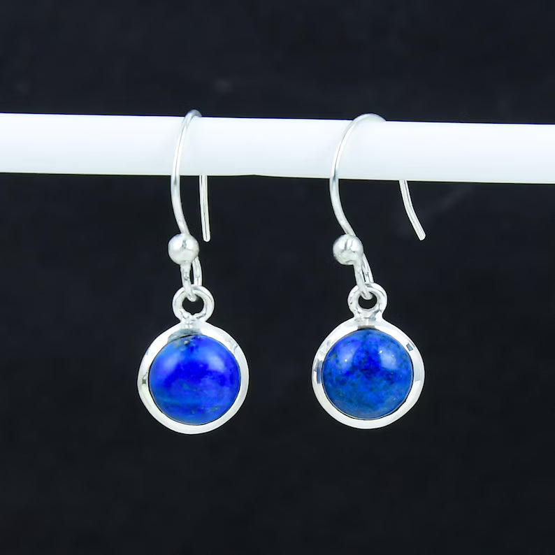 Pair of silver earrings with blue gemstones on a dark background
