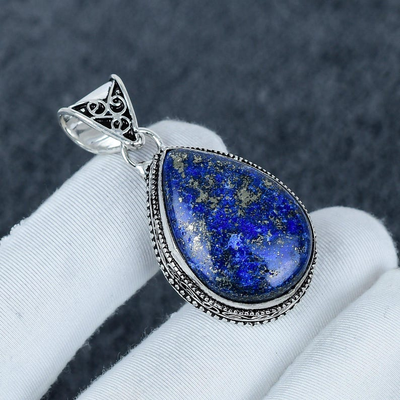 Blue stone pendant with silver frame on a white cloth background