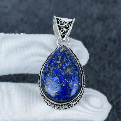 Lapis lazuli pendant with silver setting on a white cushion against a dark background