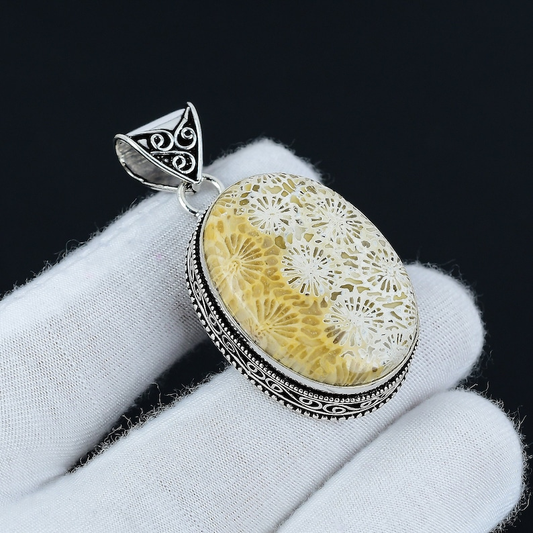 Jewelry pendant with floral design on a white glove against a black background