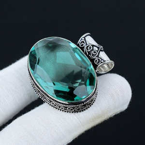Silver ring with a large green gemstone on a white cloth against a black background