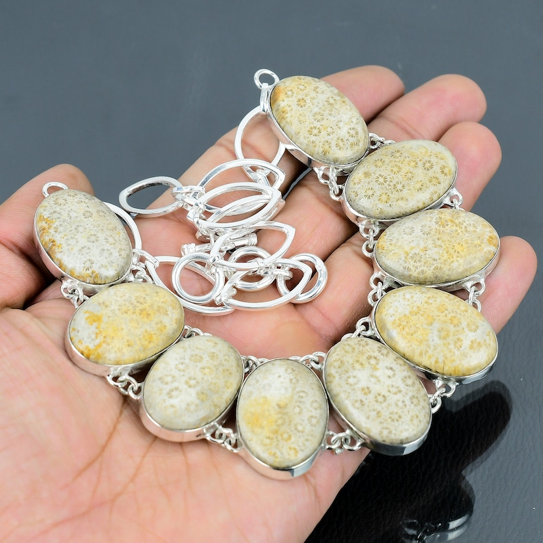 Silver bracelet with large oval stones held in a hand against a dark background