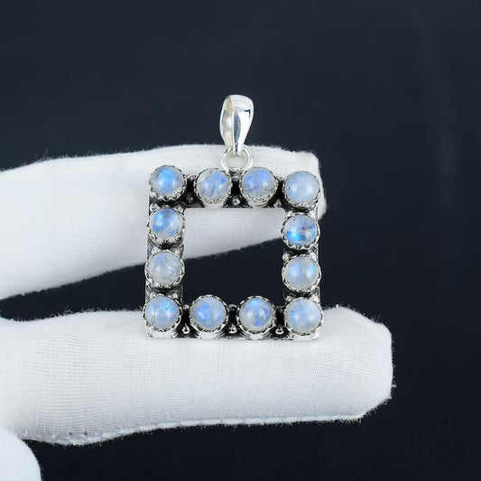 Silver pendant with blue gemstones on a white cushion against a black background