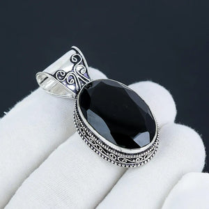 Black stone pendant with silver decorative frame on white fabric