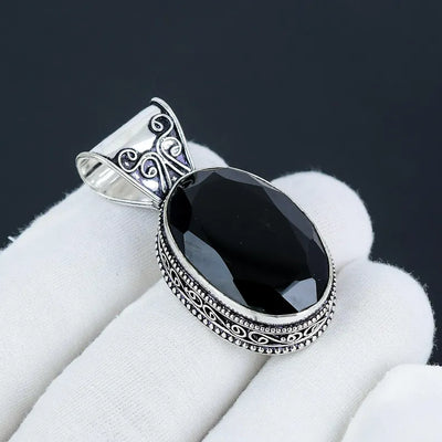 Black stone pendant with silver decorative frame on white fabric