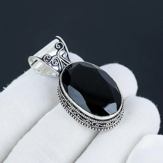 Black stone pendant with silver decorative frame on white fabric