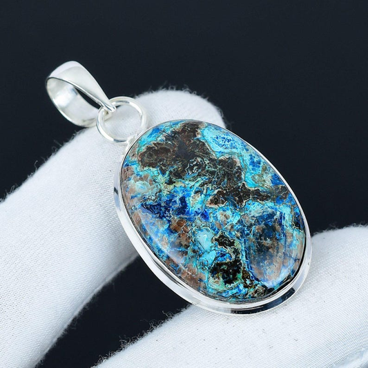 Silver pendant with a blue and brown stone on a white surface