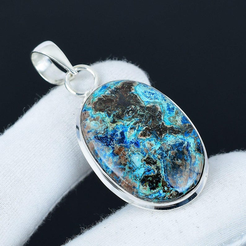 Silver pendant with a blue and brown stone on a white surface