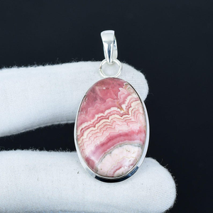 Pink stone pendant on a silver chain against a black background