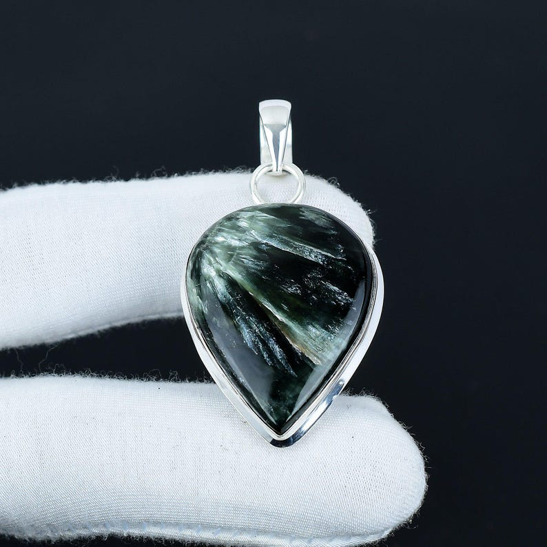 Teardrop-shaped green stone pendant on a black background