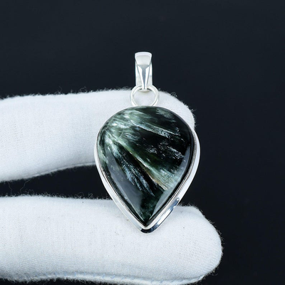 Teardrop-shaped green stone pendant on a black background