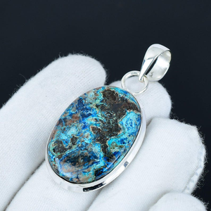 Blue and green stone pendant on a white glove with a black background