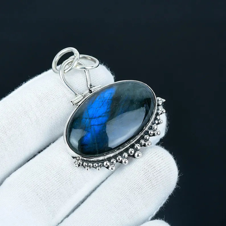 Silver pendant with a blue stone on a white cloth against a black background