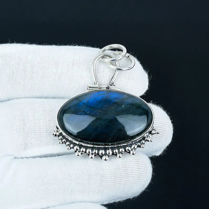 Blue stone pendant with silver setting on a white cloth background