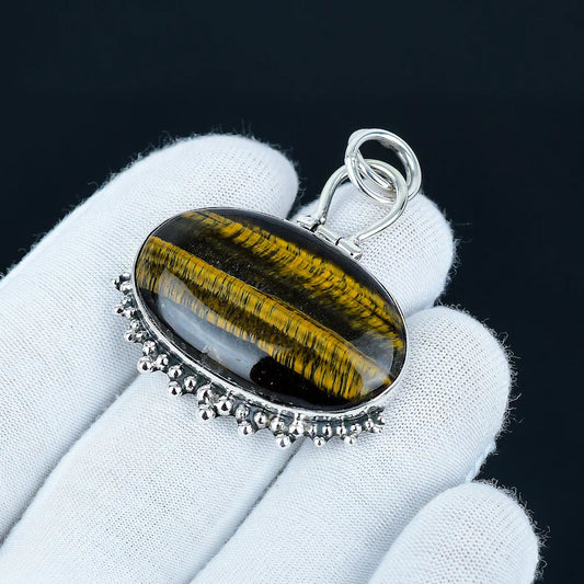 Tiger's eye pendant with silver bail on a white glove against a black background