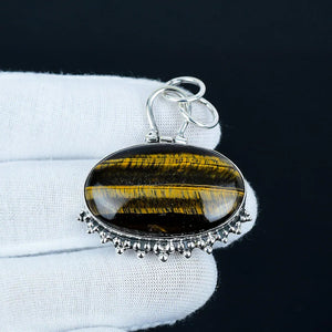 Tiger's eye pendant with silver bail on a white cushion against a black background