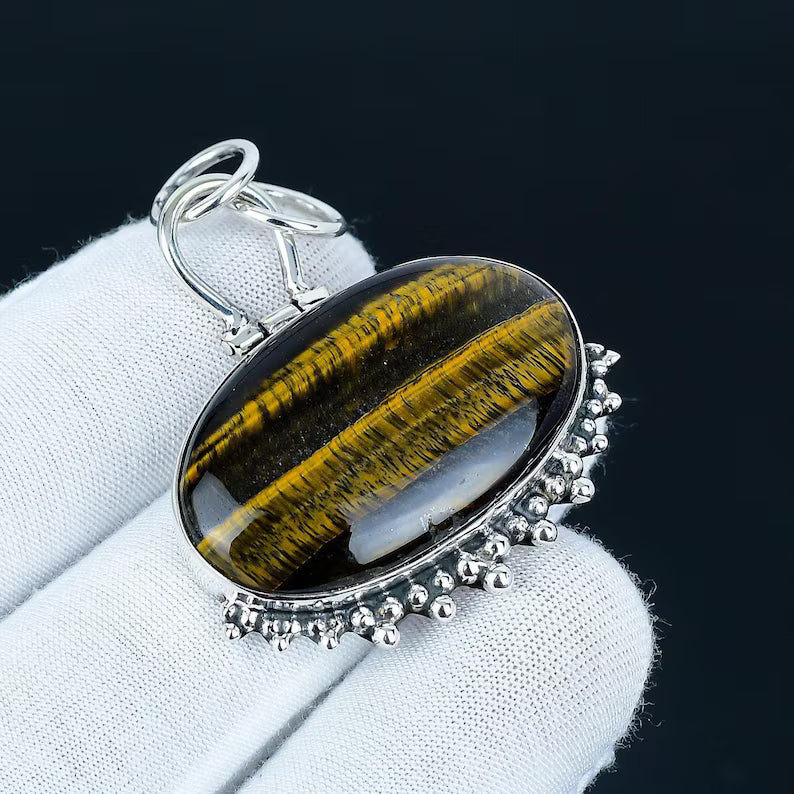 Silver pendant with a tiger's eye stone on a white cloth background