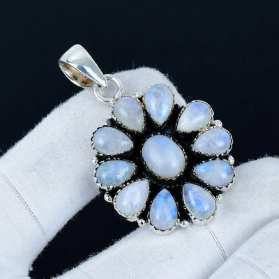 Silver pendant with blue gemstones on a white cushion against a dark background