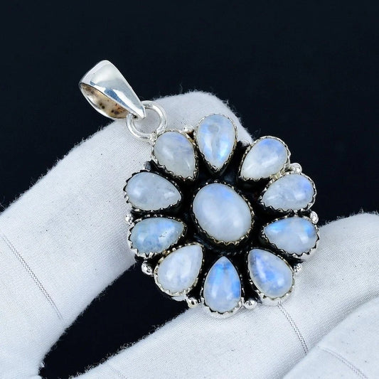 Silver pendant with blue gemstones on a white cushion against a dark background