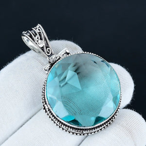 Turquoise gemstone pendant with silver frame on white fabric