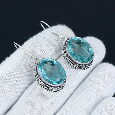 Aqua Apatite gemstone earrings on a white glove with a black background