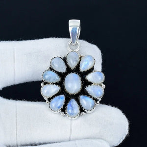 Silver pendant with blue gemstones on a white glove against a black background