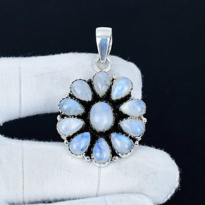Silver pendant with blue gemstones on a white glove against a black background