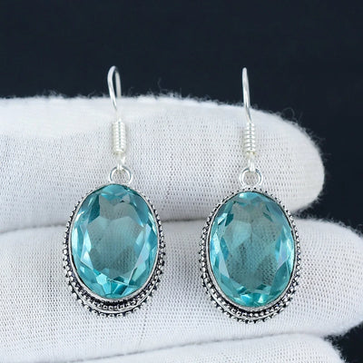 Pair of blue gemstone earrings on a white surface with a dark background