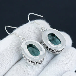 Silver earrings with green stone on a white fabric background