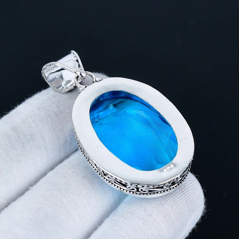 Silver pendant with blue stone on a gray surface
