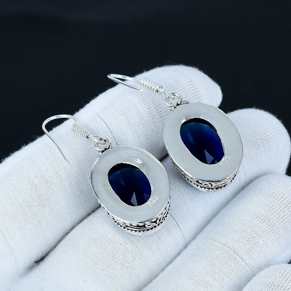 Silver earrings with blue stones on a white cloth background
