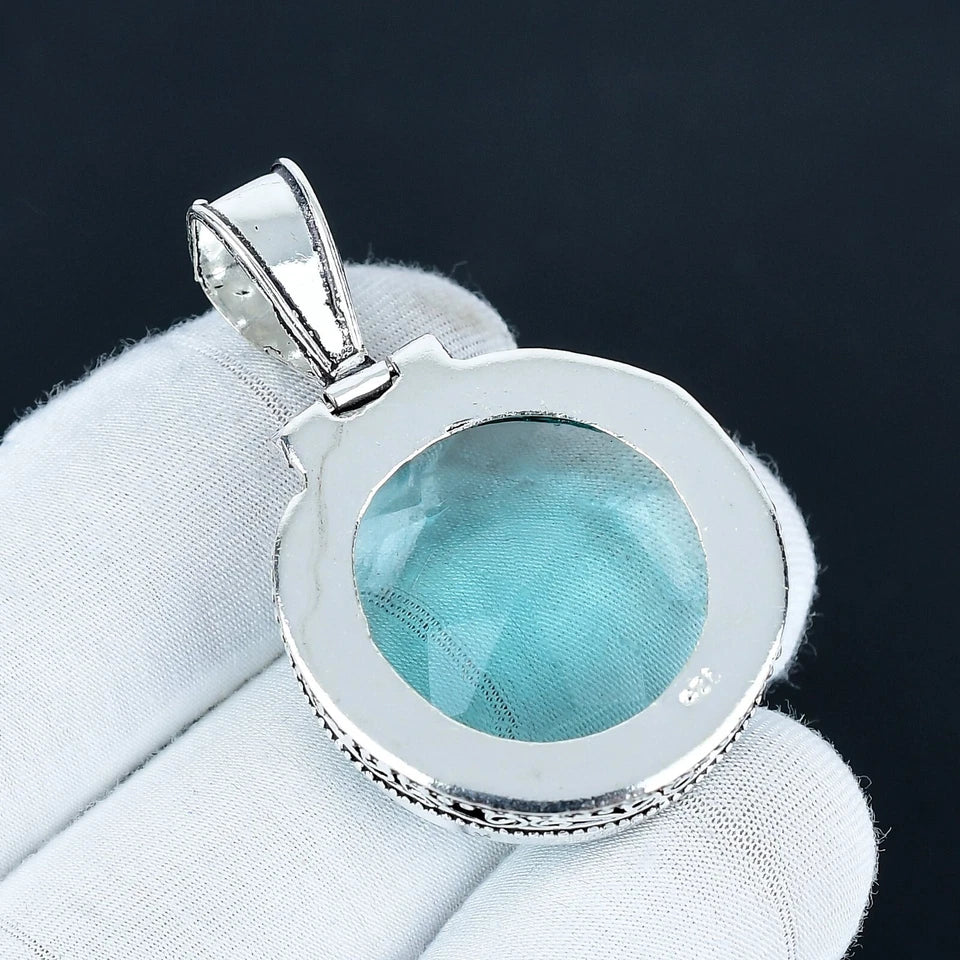 Silver pendant with a blue gemstone on a white cloth background